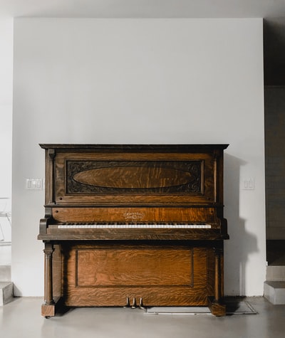 白色墙壁旁的棕色木制竖直钢琴